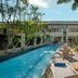 Downtown Villas Kuta poolside with loungers, tropical palms, and a covered outdoor seating area