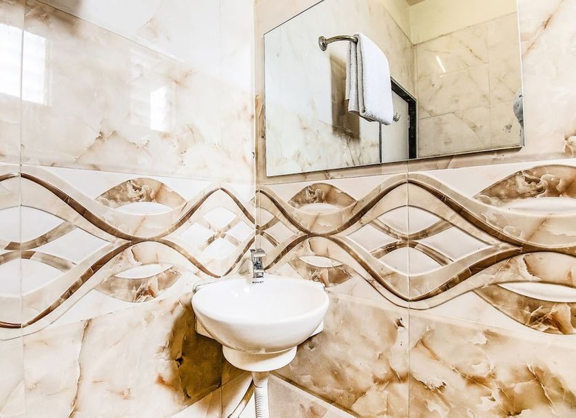 Fabhotel Adore Inn Mumbai bathroom sink with marble-style wall tiles and mirror