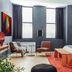 Mint House at 70 Pine, New York guest room with two chairs, large windows, and a bed beside an orange rug.