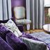 Bofors Hotel in Karlskoga with a purple sofa, floral pillows, chair, and vase of white flowers