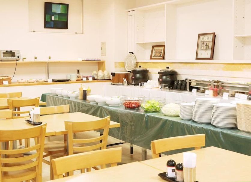 Breakfast buffet area at Smile Hotel Kumagaya in Kumagaya with tables, chairs, and serving dishes