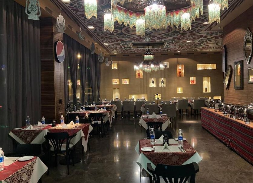 Asdal Boutique Hotel Seef in Manama restaurant with set tables, buffet line, and ornate ceiling lighting