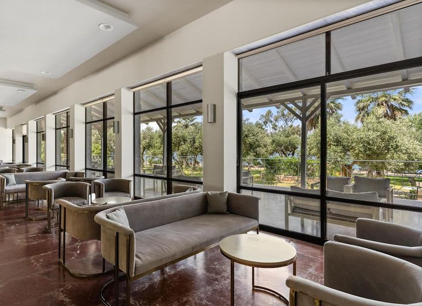 Calamos Beach Family Club in Agii Apostoli lobby lounge with seating and large windows overlooking greenery