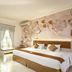 Lombok Garden Hotel in Mataram, bedroom with king bed, window bench, and floral wall art