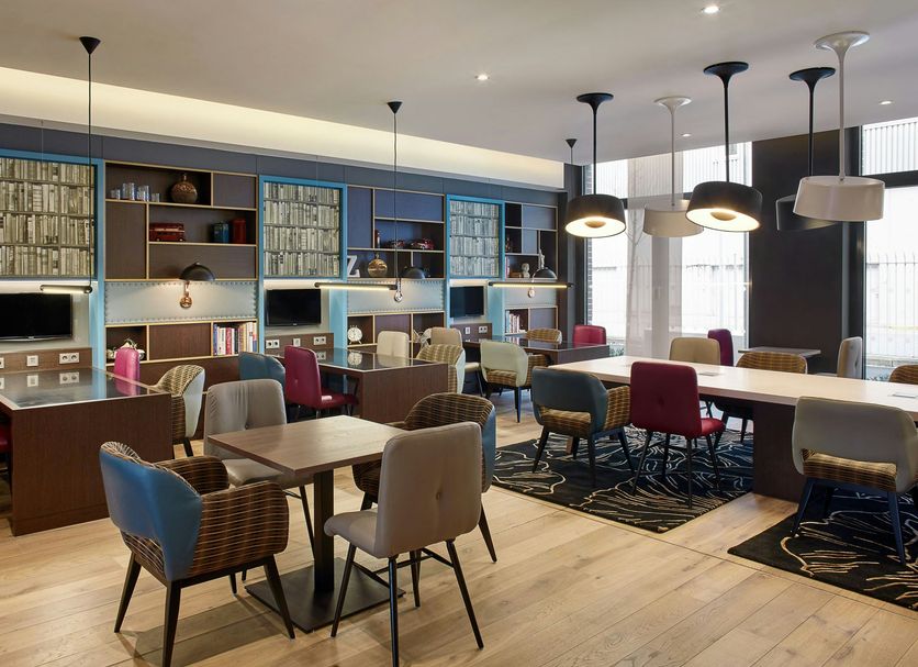 Premier Inn Frankfurt Messe lobby lounge with tables, chairs, shelving and pendant lights in Frankfurt am Main