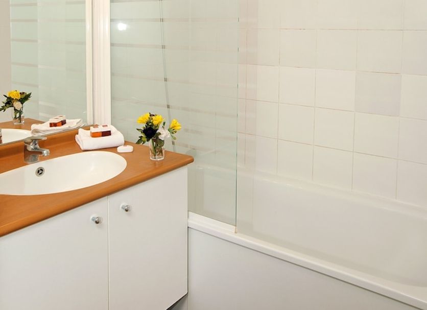Séjours & Affaires Genève Saint Genis bathroom with bathtub, shower, vanity and mirror in Saint-Genis-Pouilly