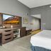 Hampton Inn Buffalo - Amherst guest room with king bed, dresser, TV and gray walls in Amherst