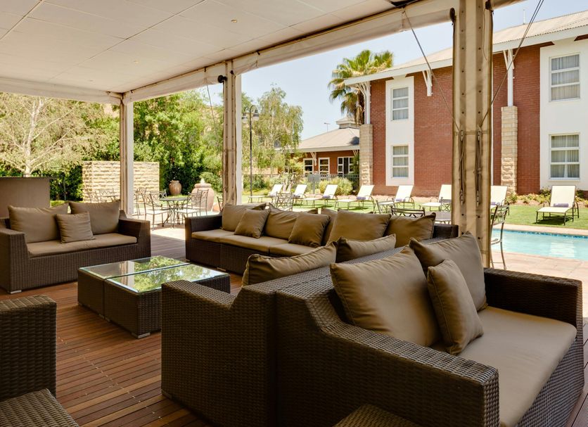 Protea Hotel by Marriott Bloemfontein poolside patio with wicker seating and outdoor pool view