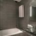 AC Hotels by Marriott Bologna bathroom with tub, glass sink, and illuminated mirror