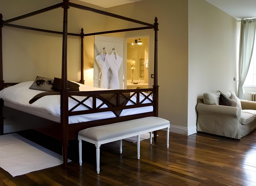 Hotel Domaine De Raba Bordeaux Sud bedroom with four-poster bed, bench, and sitting area in Bordeaux