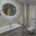 Rosy Suites Hotel Kusadasi bathroom with sink, round mirror, toilet and glass shower