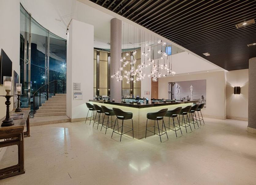 Lobby lounge at Radisson Blu Hotel, Milan with curved glass stairs and central bar seating