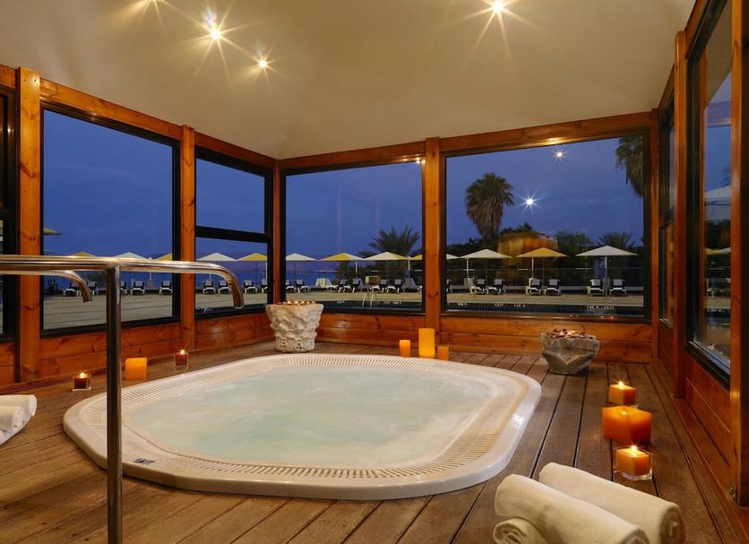 Leonardo Plaza Hotel Tiberias in Tiberias features a wood-paneled spa pool with lakefront views at dusk