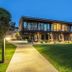 Domaine de Bayeux in Bayeux, modern hotel exterior with lit walkway and landscaped lawn at dusk