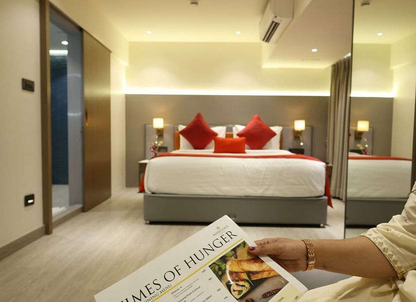 Marigold-Newly Renovated Hotel, Shirdi: modern guest room with king bed and a guest reading a magazine