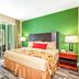 Mizner Place at Weston Town Center bedroom with king bed, green accent wall and balcony view in Weston