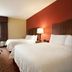 Hampton Inn Battle Creek guest room with two beds, TV, desk, and window view