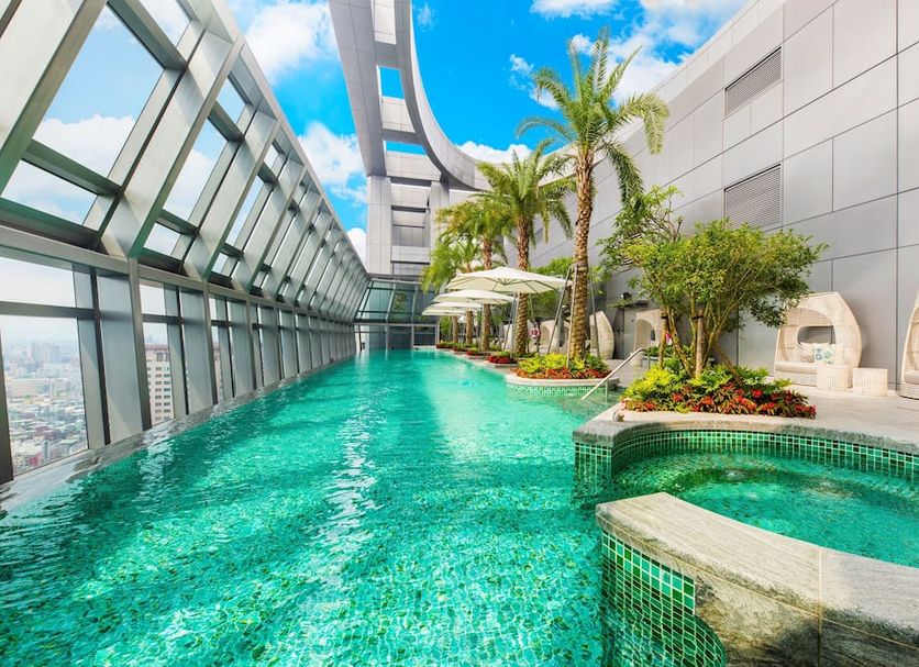 Caesar Park Hotel Banqiao rooftop pool with city views, palm trees and sun loungers