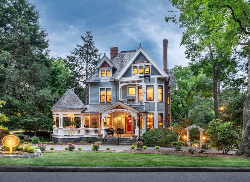 1899 Wright Inn & Carriage House in Asheville, Victorian inn exterior with lit windows and landscaped garden