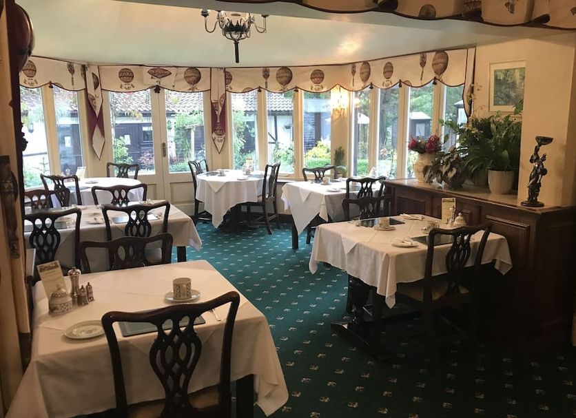 West Lodge Hotel in Aylesbury dining room with set tables, patterned carpet, and garden-facing windows