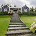 Los Ponchos Hotel in El Calafate with a landscaped lawn, staircase, and cottage-style exterior