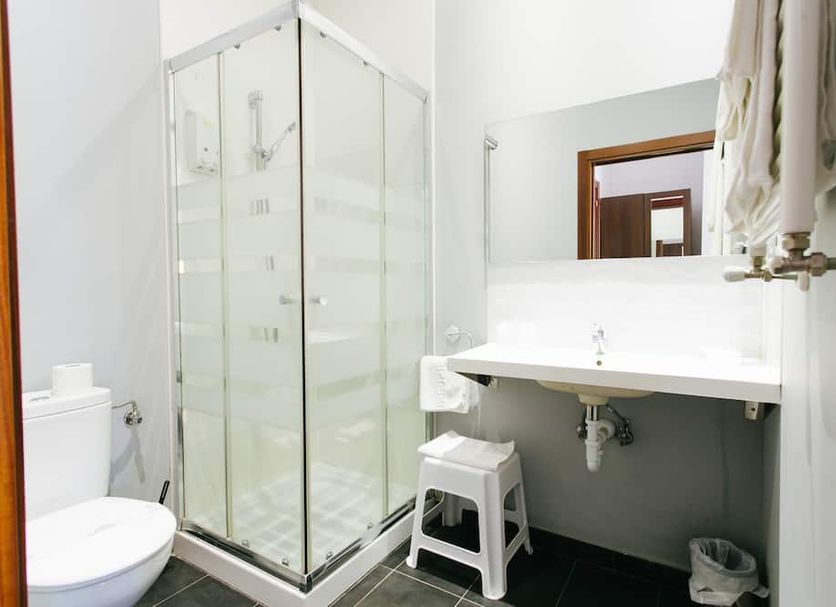 Hostal San Ignacio Centro bathroom in San Sebastian with glass shower, toilet, sink and mirror