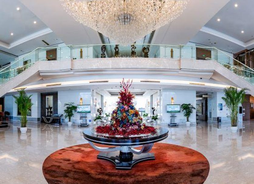 Haiqing Hotel Qingdao grand lobby with chandelier, glass balcony, and floral centerpiece
