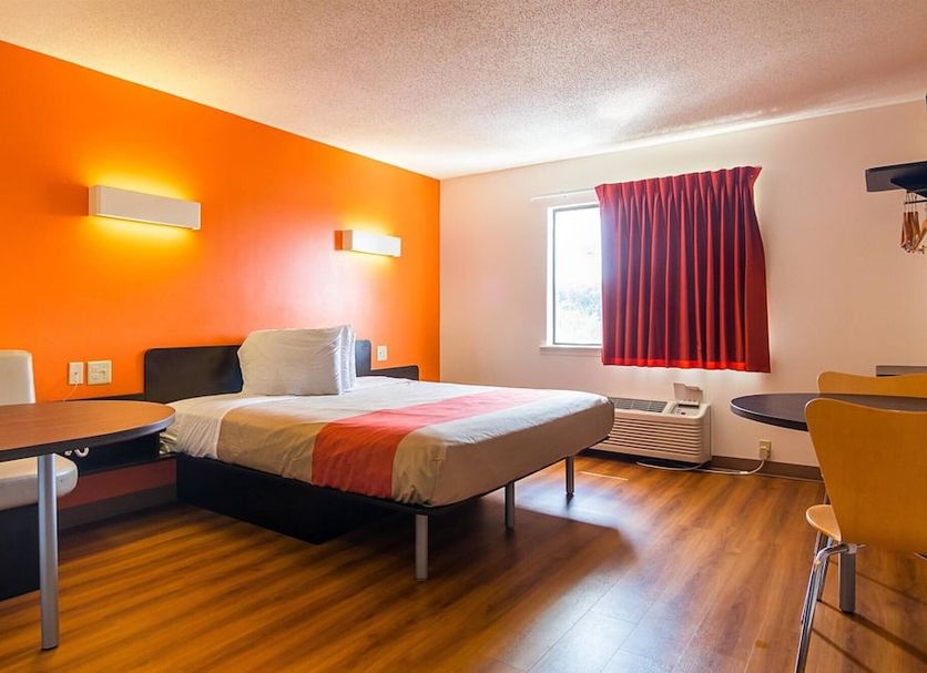 Motel 6 Jonesboro guest room with double bed, orange accent wall, window and wood-look flooring