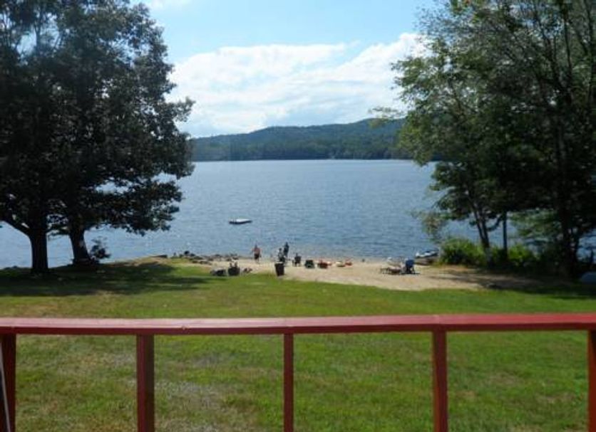 White Oak Motel & Cottages in Holderness: lakeside beach and grassy lawn with mountain views