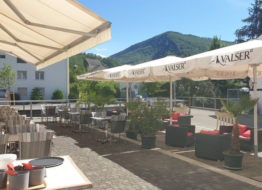 Hotel Balsthal terrace with umbrellas, outdoor seating, and mountain views in Balsthal
