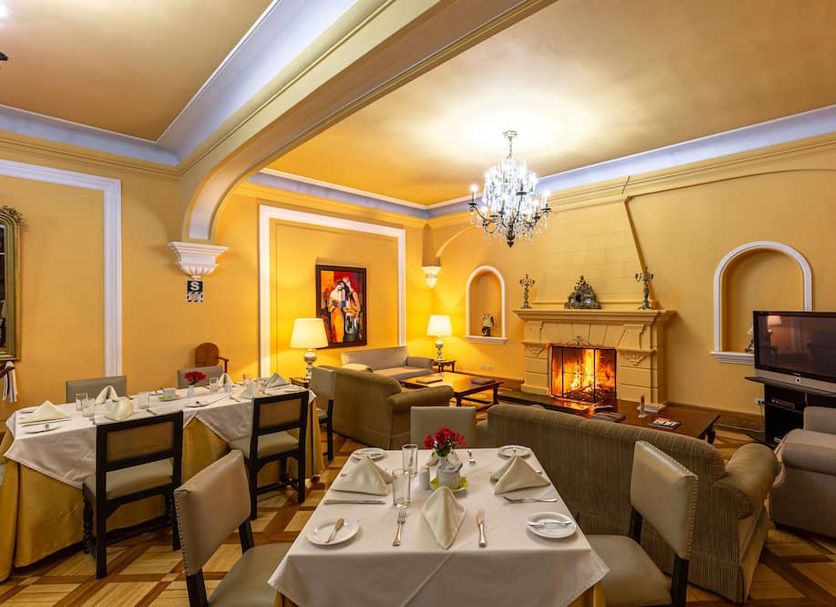 Lp Los Portales Hotel Tarma dining lounge with fireplace, chandelier, and set tables in Tarma