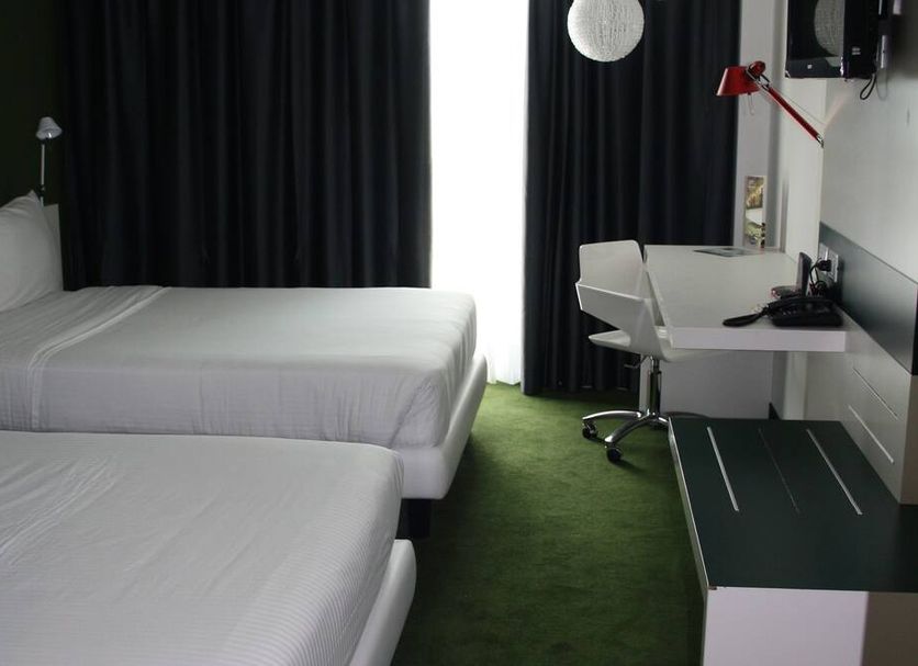 Idea Hotel Milano Malpensa Airport room in Case Nuove with two beds, desk, and green carpet
