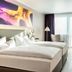 Four Points by Sheraton Offenbach Plaza room with twin beds, desk, brick accent wall and balcony doors