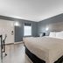 Quality Inn Laurinburg guest room with king bed, gray walls, window, and nightstands in Laurinburg
