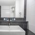 Bastion Hotel Zoetermeer bathroom with large sink, mirror, and dark tiled walls in Zoetermeer