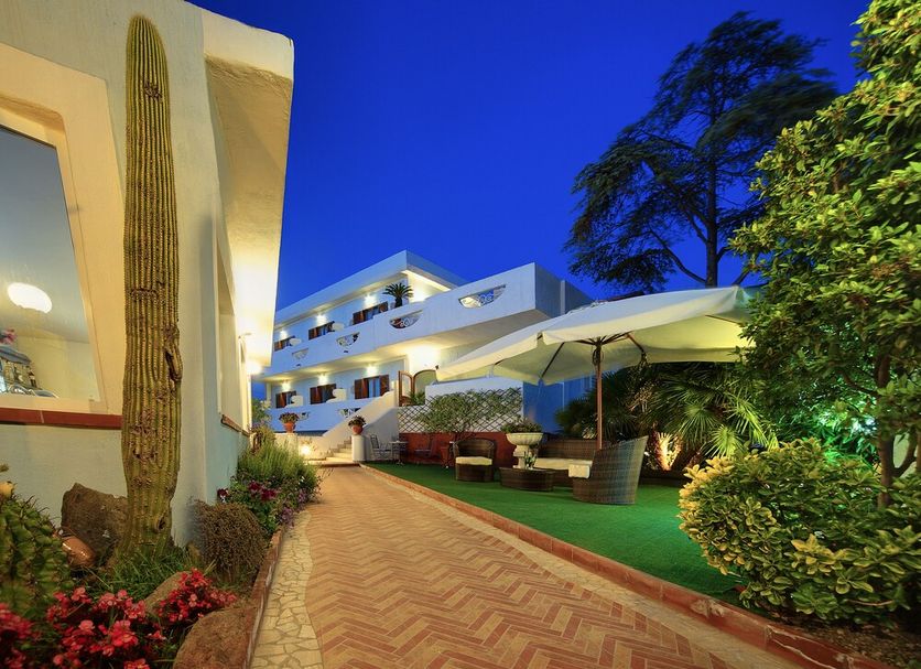 Iris Hotel Forio courtyard walkway with landscaped garden and outdoor seating at dusk