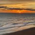 Sunset over the ocean at Royal Floridian Resort by Spinnaker in Ormond Beach, with waves on the shore.