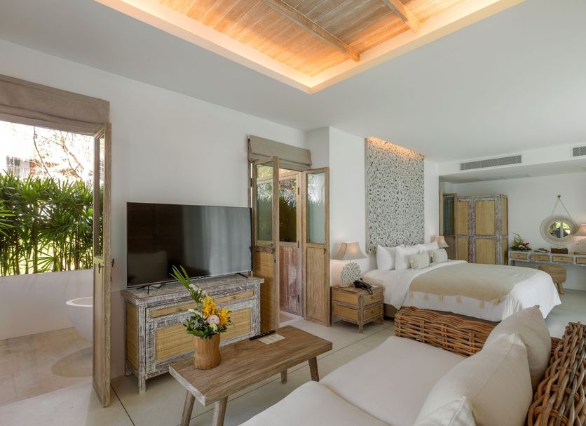 Eden Beach Khao Lak Resort & Spa room in Thai Mueang with wicker sofa, TV, bed and open patio doors