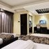 Hotel The Capital in Dhaka guest room with multiple beds, TV, desk, chair and curtained window