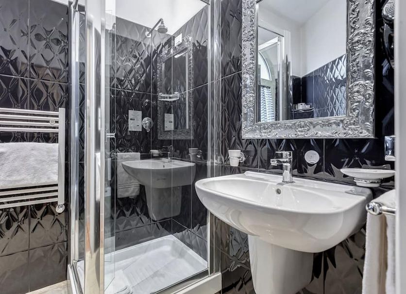 Navona Queen Rooftop Rome bathroom with walk-in shower, white sink, mirror and black tiled walls