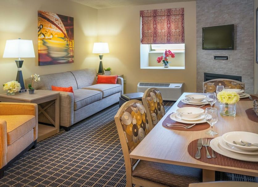 Patriots Inn Williamsburg suite with dining table, sofa, armchair, lamps, TV and window seating area