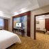 Haili Garden Hotel Guangzhou guest room with king bed, TV, and adjoining sitting area