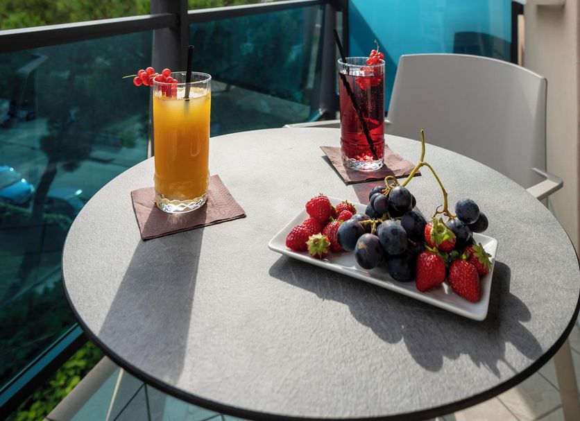 Olimpia Hotel & Aparthotel balcony with table, drinks, fruit tray and glass railing in San Michele al Tagliamento