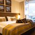 Hotel Stadt Kufstein guest room with bed, plaid armchair, and open balcony doors in Kufstein