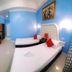 Sunny Point Hotel, Davao City: twin beds in a bright blue guest room with wall-mounted TV and desk