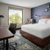 Four Points by Sheraton Brunswick guest room with king bed, desk, and large window with tree view