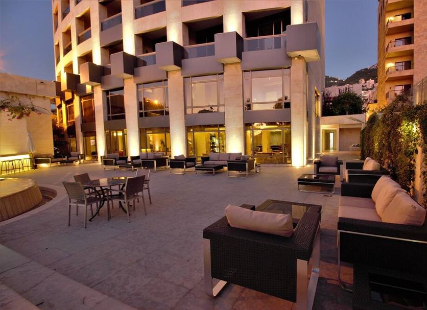 The Rooms Boutique Hotel, Jounieh: outdoor terrace with seating and illuminated hotel facade at dusk