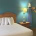 Motel 6 Portland, IN guest room with double bed, nightstand, wall lamp, towel rack, and mini fridge