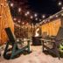 Gravity Haus Revelstoke outdoor fire pit lounge with string lights and Adirondack chairs in snow