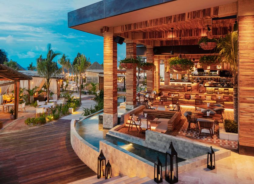 Jungala Hotel at VidantaWorld Riviera Maya in Cancún with outdoor dining and lagoon-side seating at sunset